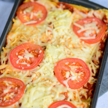 Easy vegan lasagna baked with sliced tomatoes and melted vegan cheese