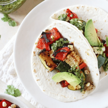 Grilled veggie tacos with chimichurri on a white plate