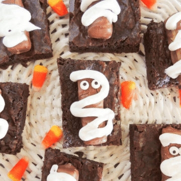 Halloween mummy brownies decorated with Twix bars, candy eyes and white icing on a woven tray