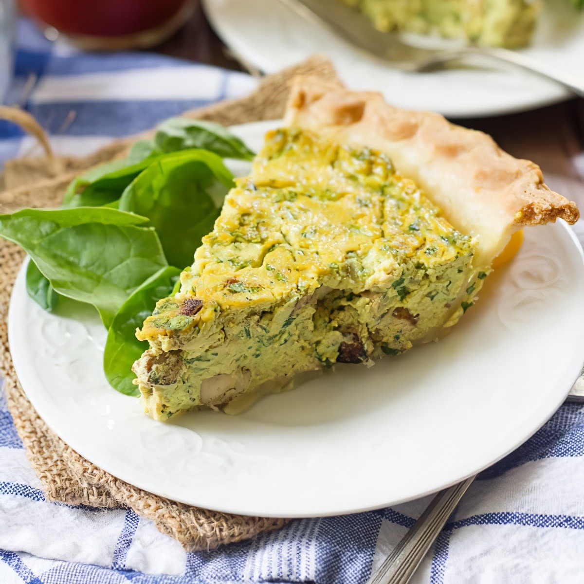 Slice of vegan tofu quiche with spinach on a white plate