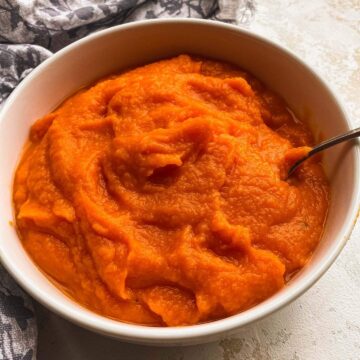 Homemade pumpkin puree in a white bowl with a spoon