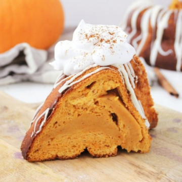Slice of one-bowl pumpkin cake topped with whipped cream and a white chocolate drizzle