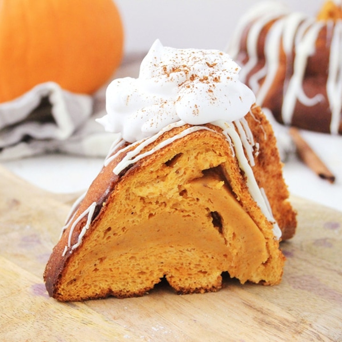 Slice of one-bowl pumpkin cake topped with whipped cream, cinnamon and white chocolate drizzle