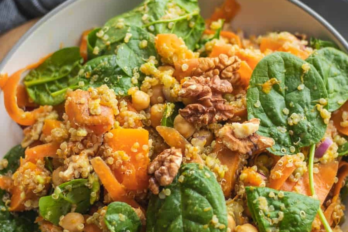 Close-up of roasted pumpkin, quinoa, chickpeas, baby spinach and walnuts in a pumpkin chickpea quinoa bowl