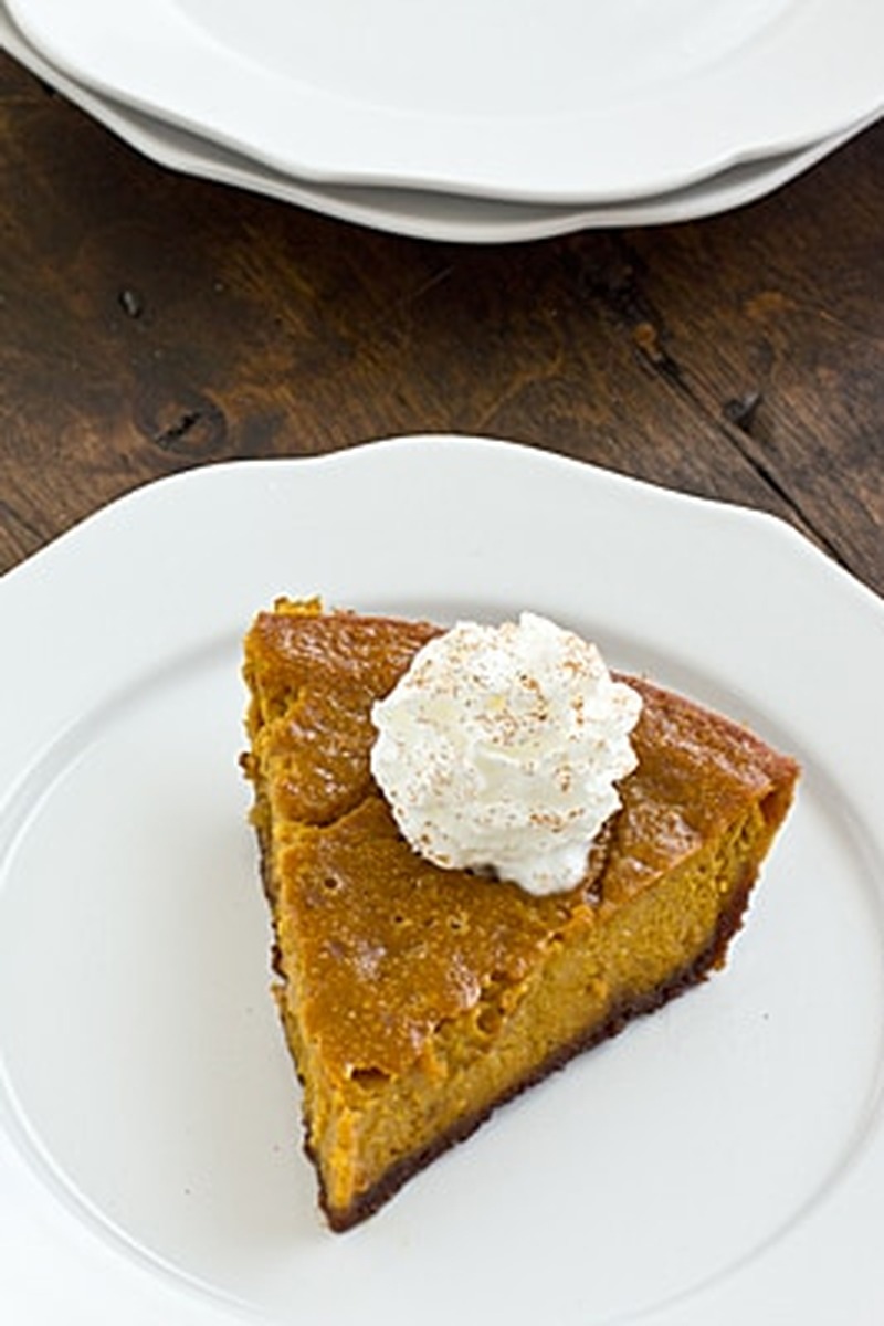Overhead view of a slice of pumpkin gingersnap pie topped with whipped cream on a white plate