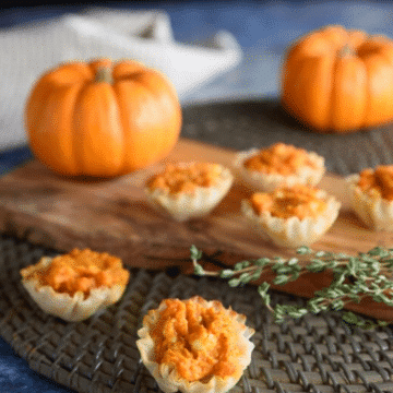 Bite-sized pumpkin puffs in phyllo cups with mini pumpkins and fresh thyme
