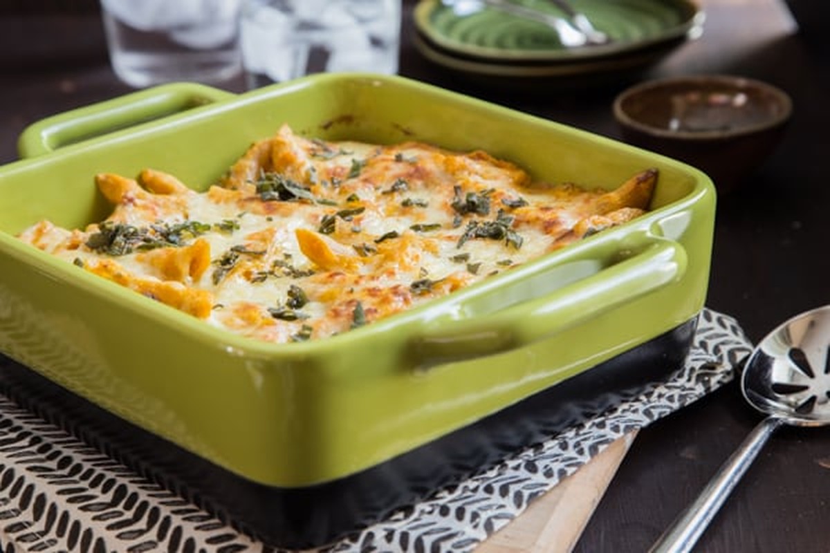Pumpkin sage baked ziti with a golden cheese top in a green baking dish