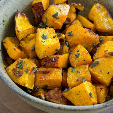 Roasted ambercup squash with brown butter and fresh sage in a stoneware bowl