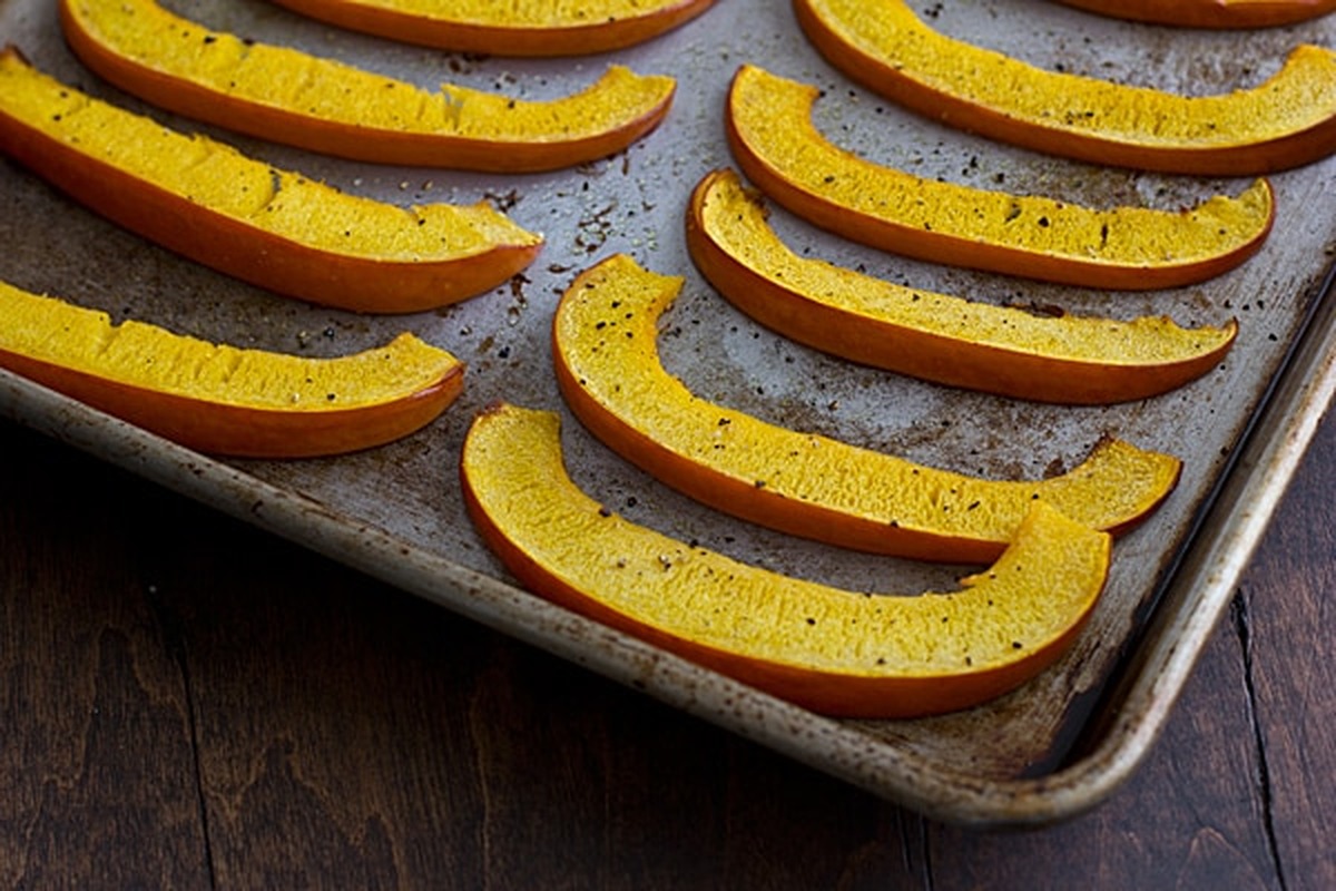 Thin roasted pie pumpkin wedges seasoned with salt and pepper on a baking sheet