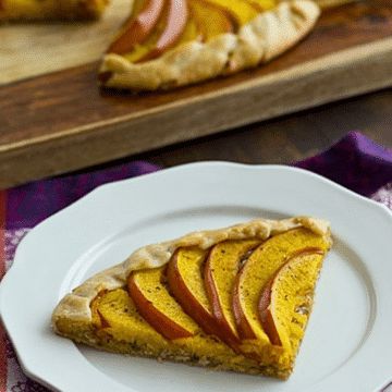 Slice of savory pumpkin galette with roasted pumpkin wedges on a white plate