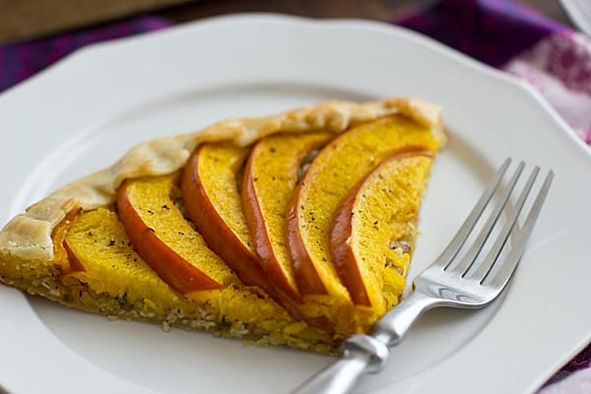 Close-up of a savory pumpkin galette slice with a flaky crust and walnut sage filling