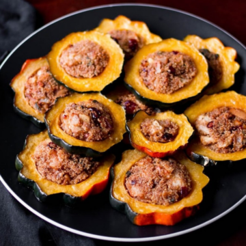 Stuffed acorn squash rings filled with quinoa, apple and cranberries on a black plate