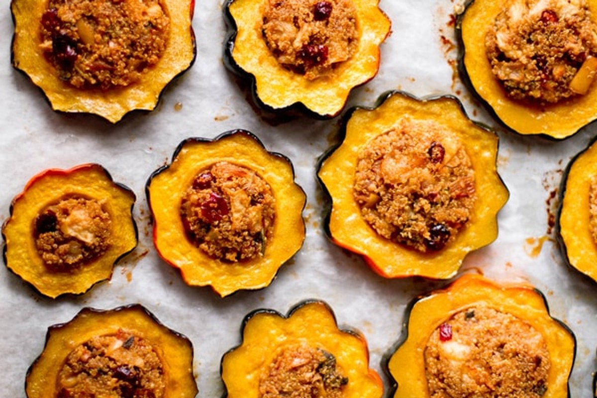 Overhead view of roasted acorn squash rings stuffed with quinoa, apple and cranberries on parchment