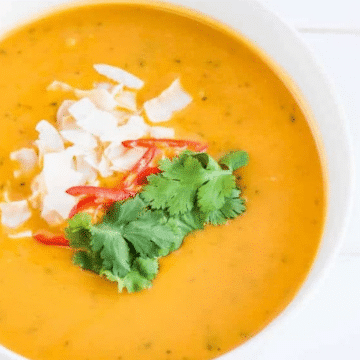 Thai pumpkin soup with coconut milk topped with coconut flakes, red chili and cilantro