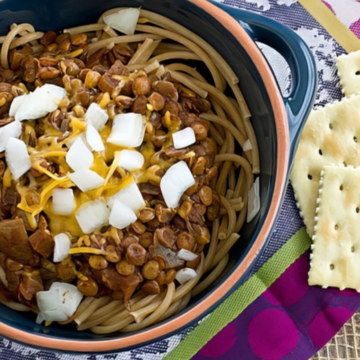 Vegan Cincinnati chili with lentils served over whole wheat spaghetti with chopped onions and cheese