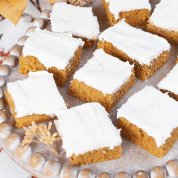 Easy vegan pumpkin bars with dairy-free cream cheese frosting on a wooden tray