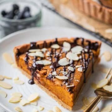 Vegan pumpkin pie slice with chocolate drizzle and sliced almonds