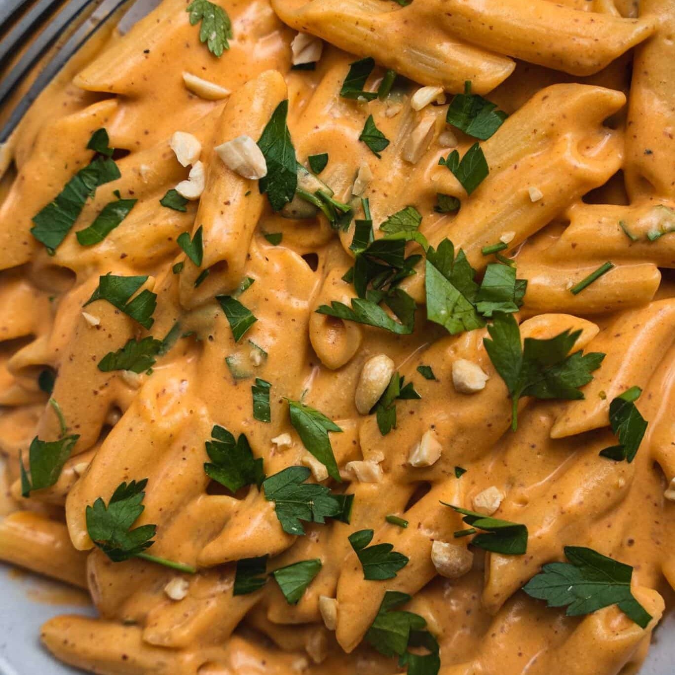 Vegan sweet potato pasta with creamy sauce, parsley and chopped nuts