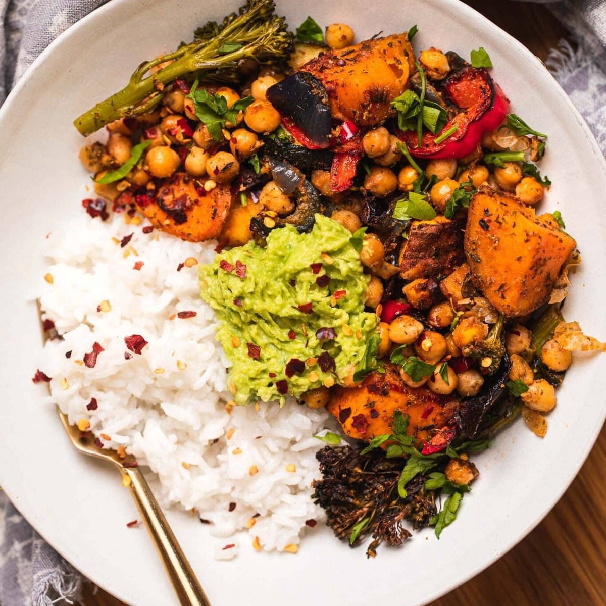 Bowl of roasted chickpeas, sweet potatoes and vegetables with rice and guacamole