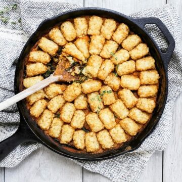 Vegetarian tater tot casserole with pumpkin, mushrooms and spinach in a cast iron skillet